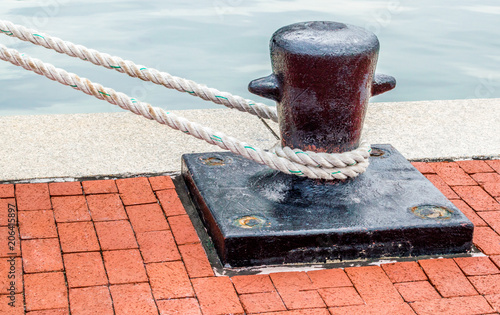 black iron ship's bollard with mooring lines on a red brick wharf at Baltimore's Inner Harbor