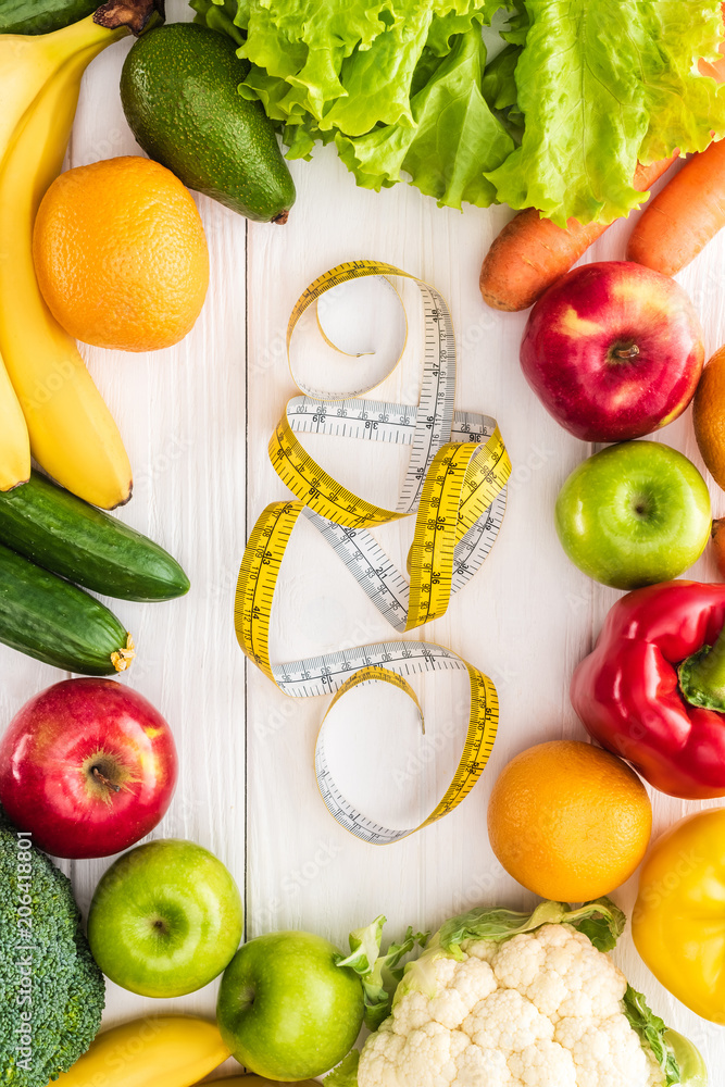 top view of fresh fruits and vegetables and measuring tape on wooden table top view of fresh fruits and vegetables and measuring tape on wooden table