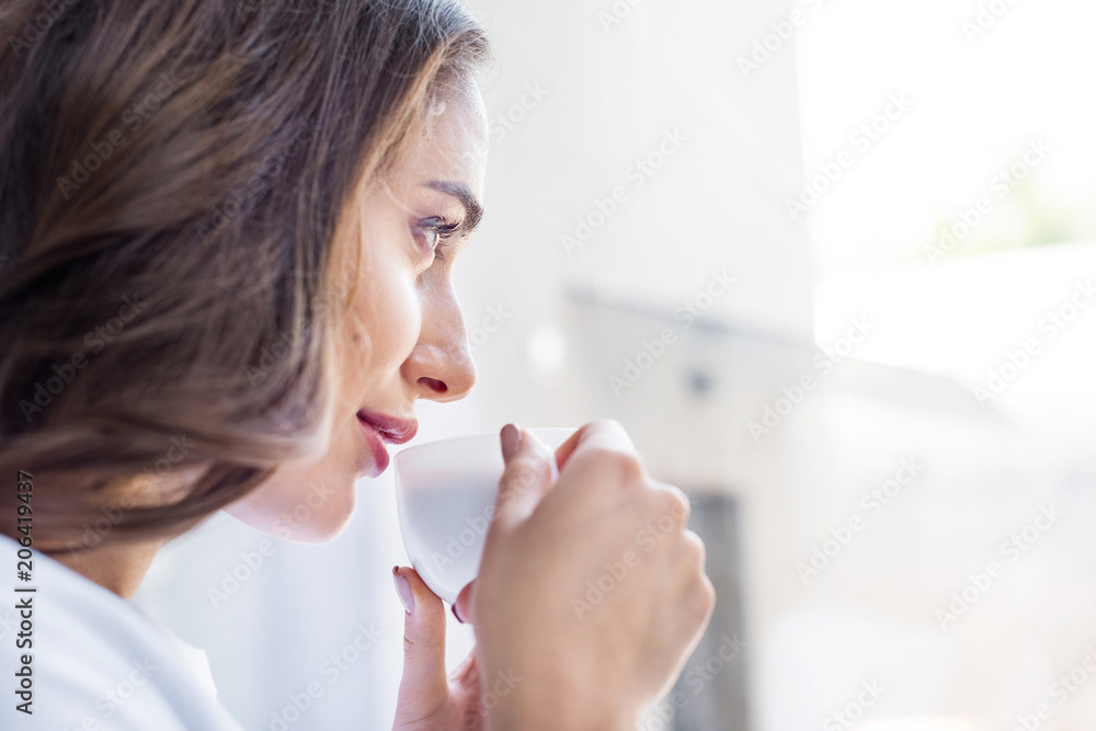 side view of beautiful brunette girl drinking coffee at home side view of beautiful brunette girl drinking coffee at home