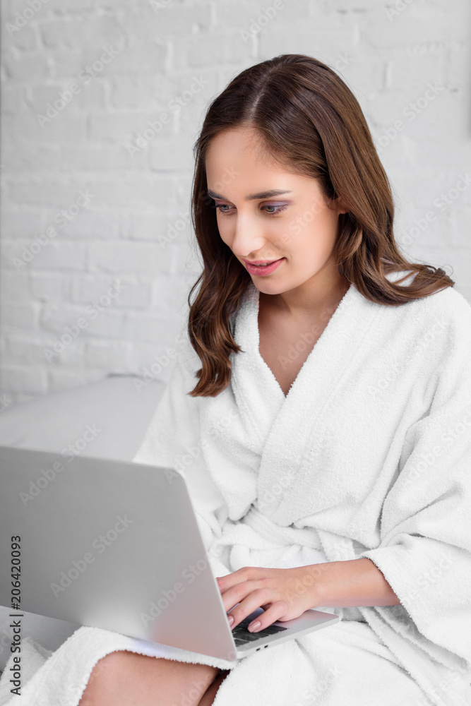 attractive young woman in bathrobe using laptop in bed attractive young woman in bathrobe using laptop in bed