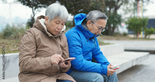 Senior couple using cellphone together at street © leungchopan