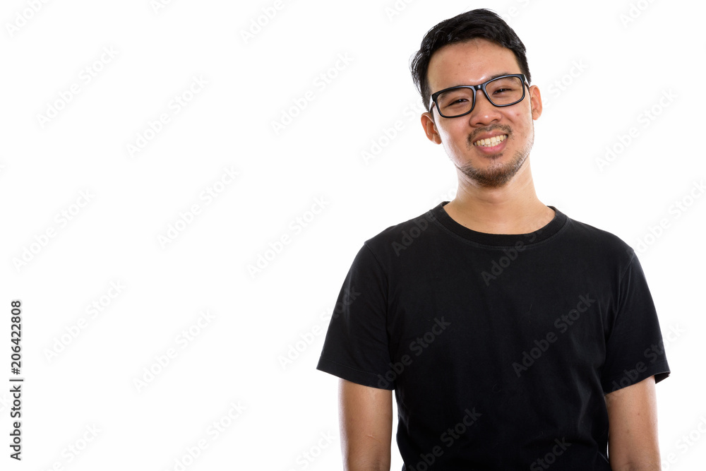 Studio shot of young happy Asian man smiling while wearing eyegl Studio shot of young happy Asian man smiling while wearing eyegl