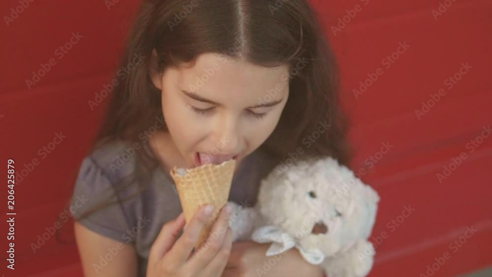 Pretty baby girl kid eating slow motion video nursing bottle licking big lifestyle ice cream in waffle cone with raspberry happy laughing on red background. the girl teenager and ice cream concept Pretty baby girl kid eating slow motion video nursing bottle licking big lifestyle ice cream in waffle cone with raspberry happy laughing on red background. the girl teenager and ice cream concept