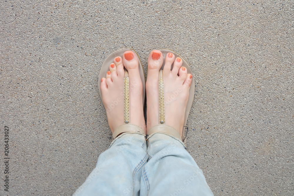 Beautiful Orange Nails Polish. Woman Slime Legs and Feet Wearing Lack of  Blue Jeans and Nude Sandals or Flip-Flop On Street Road Outdoor Stock Photo  | Adobe Stock