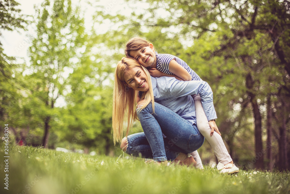 Mother and daughter on green grass.