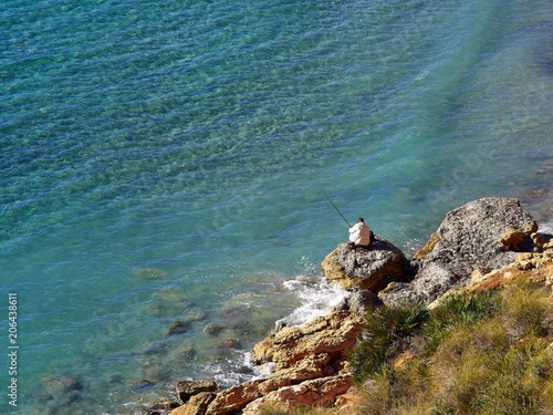 Elderly man fishing by the ocean