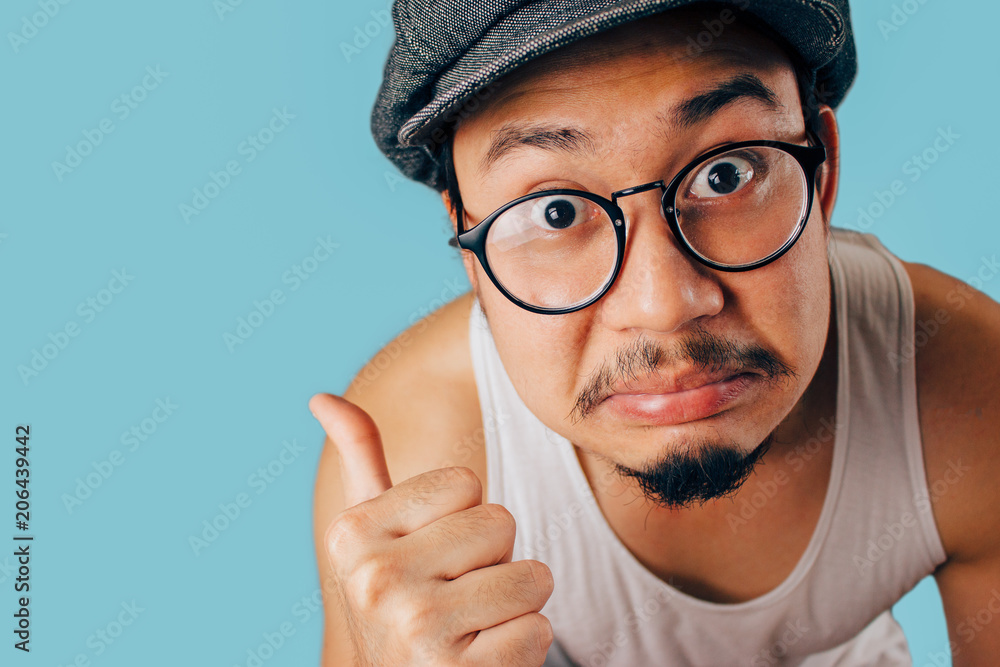Funny Asian man pointing with his thumb with disagree face on isolated ...