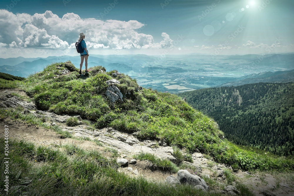 Woman hiking in mountains at sunny day time.