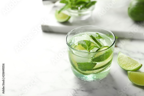 Refreshing beverage with mint and lime in glass on table