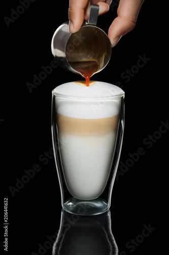 Hand with pitcher making pattern on cappuccino topping photo