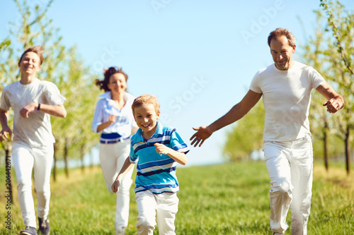 Happy family having fun walking in the garden in spring, summer. Mother, father and sons in nature.