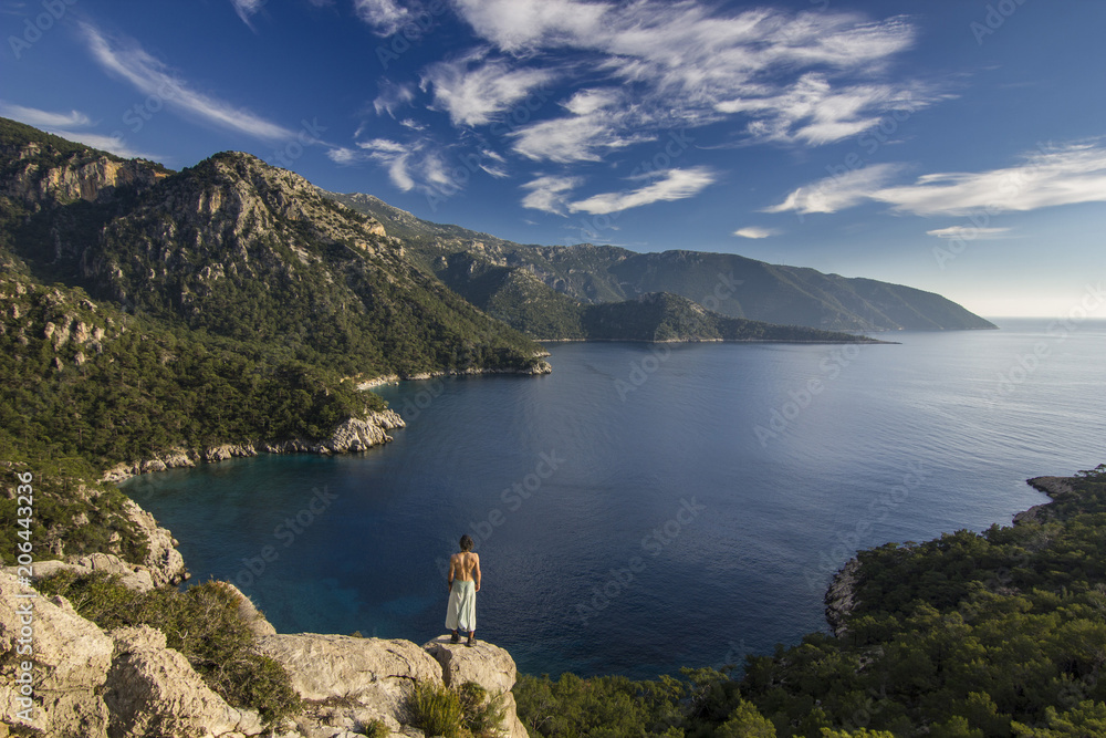 man standing on a cliff in mountains near mediterranean sea