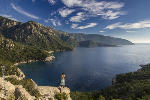 man standing on a cliff in mountains near mediterranean sea photo
