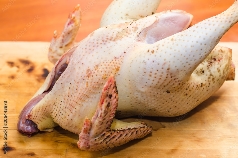 Fototapeta premium Farm raw gutted chicken on a wooden cutting board