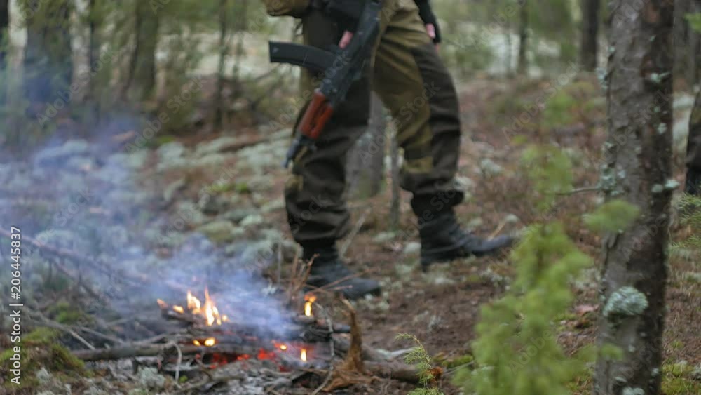 Soldiers in camouflage with combat weapons shoot at the forest shelter, military concept, smoke screen, fog Soldiers in camouflage with combat weapons shoot at the forest shelter, military concept, smoke screen, fog