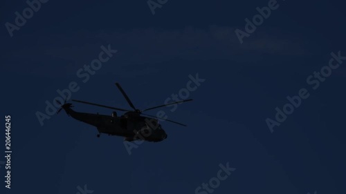 Silhouette of Military helicopter flying against night sky. 4K.