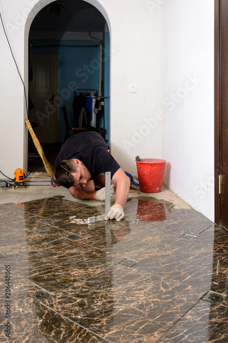 A person with a laser level checks the installed floor tile photo