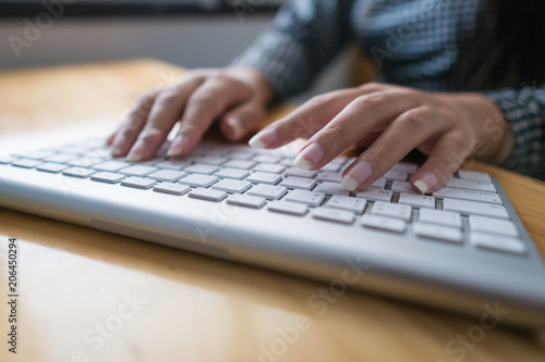 Close up hand business woman working office with computer keyboard. woman writing a blog. Female hands typing on keyboard with wood desk table