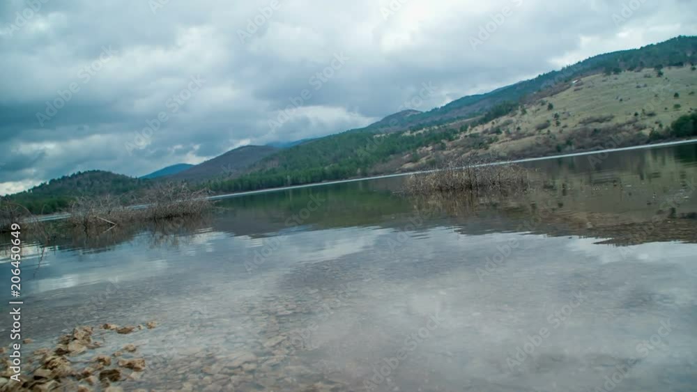 Approaching the lake. There are stones on the coast. Many hills are surrounding the lake. Approaching the lake. There are stones on the coast. Many hills are surrounding the lake.