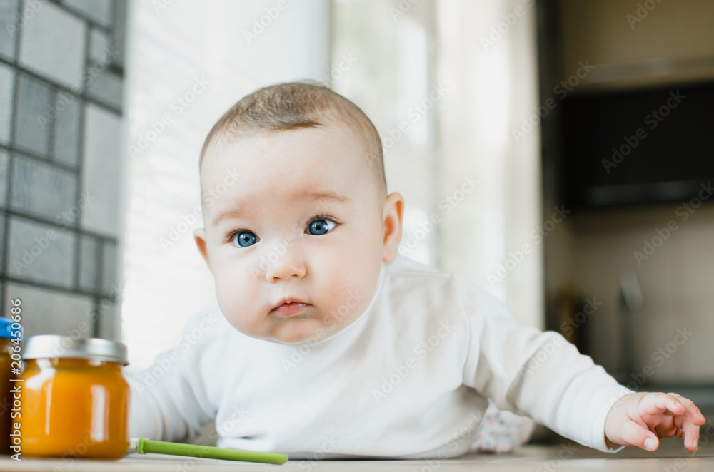 baby with blue eyes crawling, wants to eat pumpkin puree in a jar baby with blue eyes crawling, wants to eat pumpkin puree in a jar