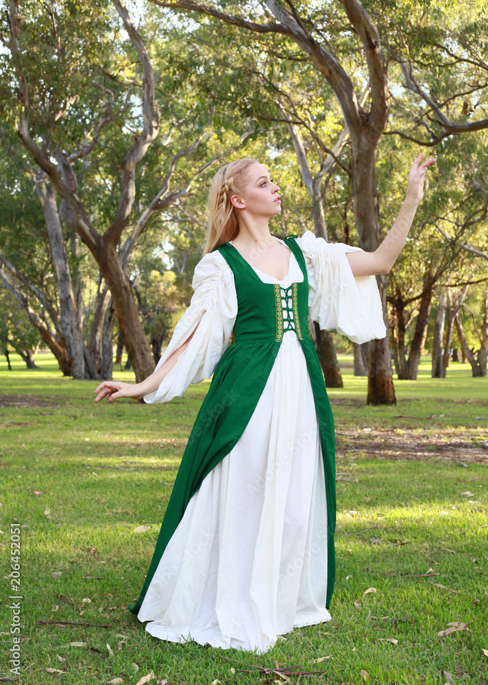 full length portrait of blonde girl wearing greensand white medieval costume, standing pose. walking through a forest. full length portrait of blonde girl wearing greensand white medieval costume, standing pose. walking through a forest.