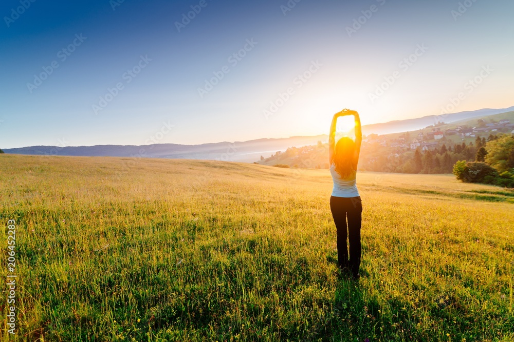 Woman enjoying beautiful sunrise at mountains.