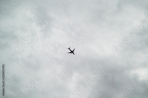 silhouette of airplane  through a stormy and cloudy grey sky