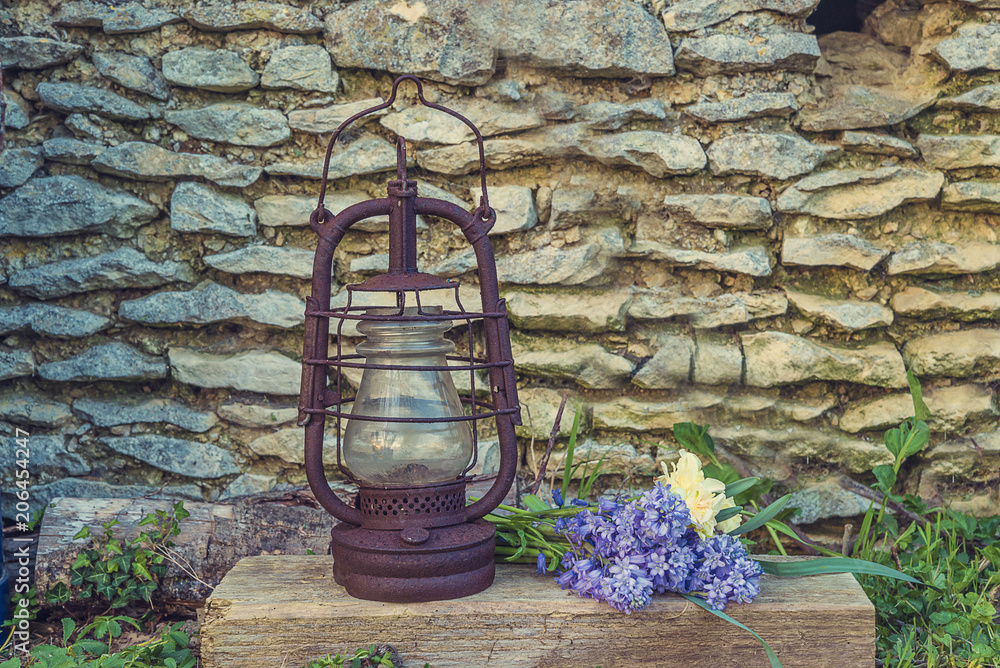 Old hurrican lamp and bouquet of blue hyacinths against old stones wall