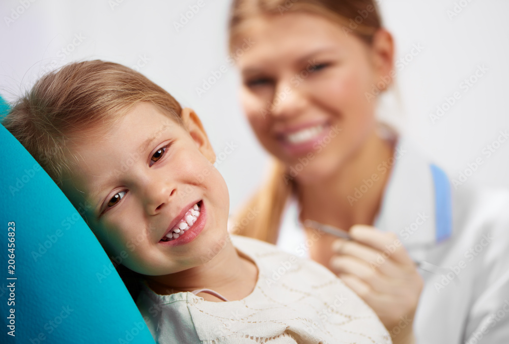 Smiling girl sitting at dentist chair, examining teeth. Dental care concept. Smiling girl sitting at dentist chair, examining teeth. Dental care concept.