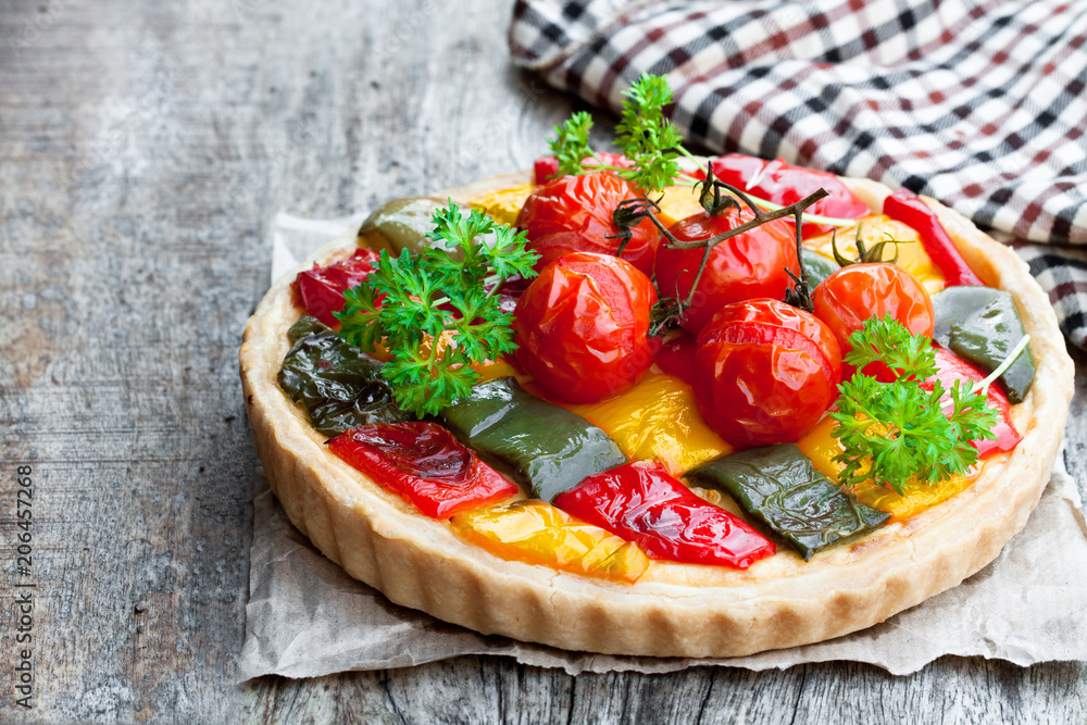 Vegetarian  quiche with colored pepper and cherry tomatoes on wooden table