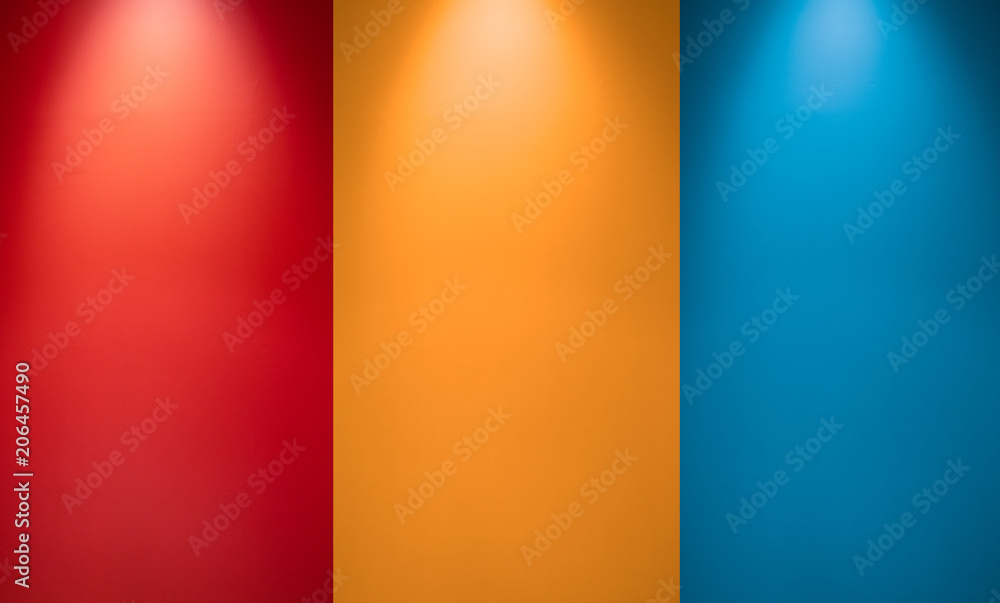 Empty red, orange or yellow and blue wall with spotlights. Illuminated lamp light. Room  interior with ceiling lamp light and colorful wall. Studio wall texture background