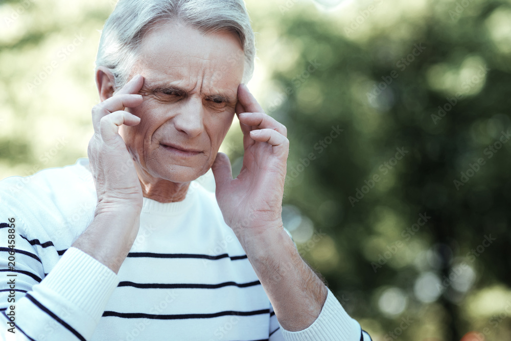 Try to concentrate. Attentive man wrinkling forehead and touching temples while having some thoughts Try to concentrate. Attentive man wrinkling forehead and touching temples while having some thoughts