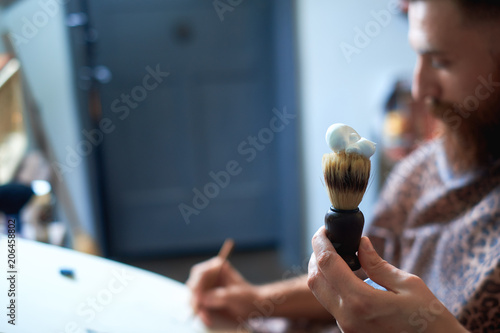 4683351 Close up of a hairdresses work for an attractive young blond man at the barber shop. He is doing styling of his beard, shaving with straight razor photo