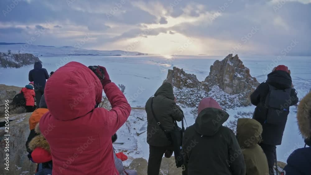 RUSSIA, OLKHON - MARCH 1, 2018: Large group of tourist watching and taking photos of famous sunset view in Lake Baikal. RUSSIA, OLKHON - MARCH 1, 2018: Large group of tourist watching and taking photos of famous sunset view in Lake Baikal.