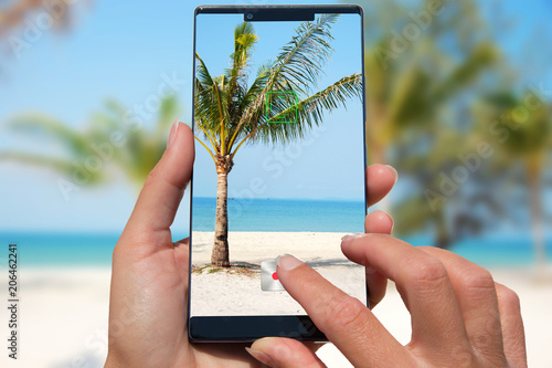 Photography Woman with mobile phone photos exotic beach.