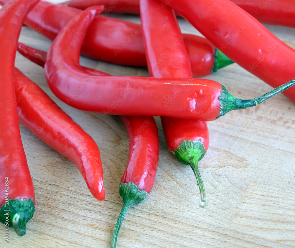 Many red hot chilli peppers on brown wooden surface top view closeup Many red hot chilli peppers on brown wooden surface top view closeup