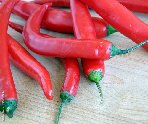 Many red hot chilli peppers on brown wooden surface top view closeup