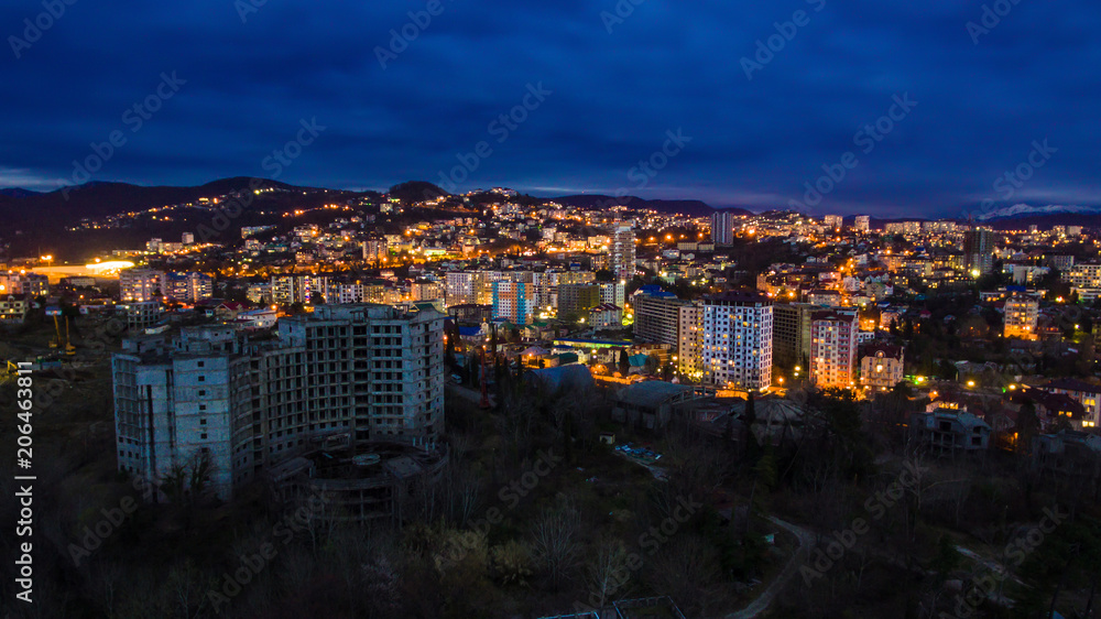 Drone view of the seaside with the illuminated district of the city of Sochi at dusk, Russia
