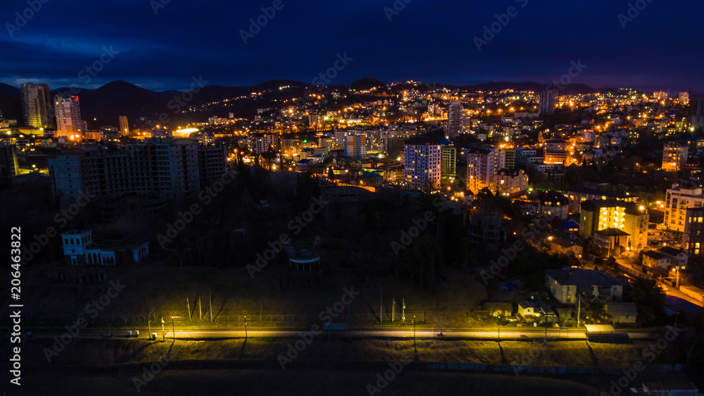 Drone view of the seaside with the illuminated district of the city of Sochi at dusk, Russia
