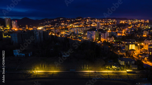 Drone view of the seaside with the illuminated district of the city of Sochi at dusk, Russia 