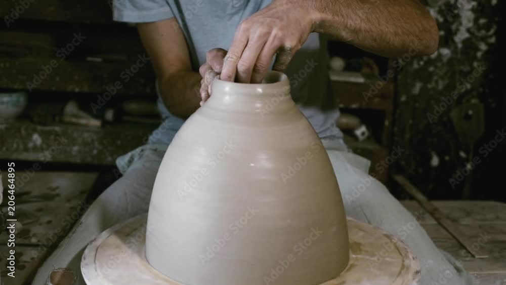 Potter make clay jar with wide neck on rolling potter's wheel Potter make clay jar with wide neck on rolling potter's wheel