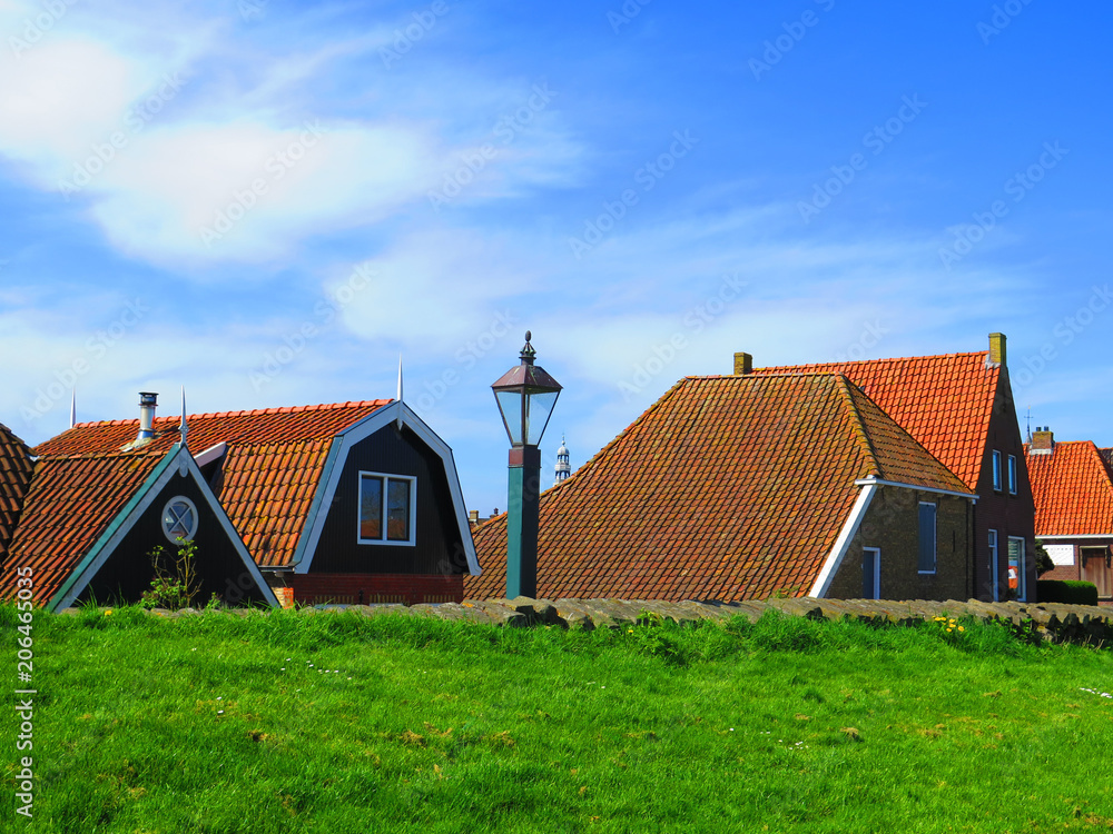 Rooftops visible behind dike in Dutch fishing village Rooftops visible behind dike in Dutch fishing village