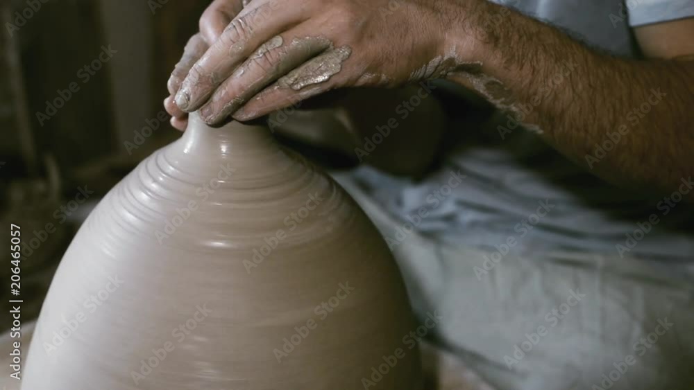 Potter make clay jar with narrow neck on rolling potter's wheel Potter make clay jar with narrow neck on rolling potter's wheel