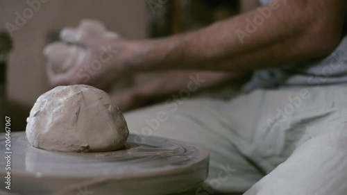 Closeup rolling potter's wheel with piece of clay and poter on background photo