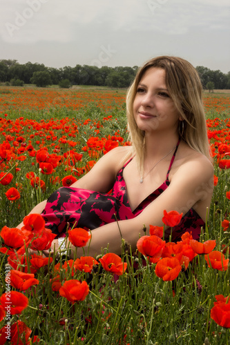 Beautiful, young blond girl, in a beautiful dress among the poppy fields.