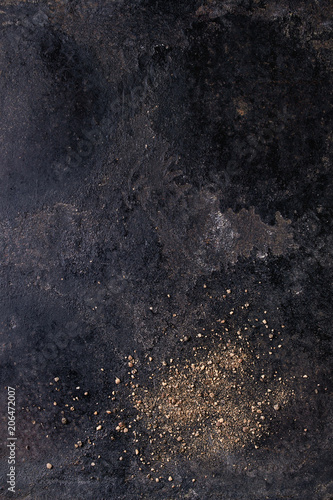Groung black pepper powder over old black iron texture surface. Top view, space. Food background © Natasha Breen