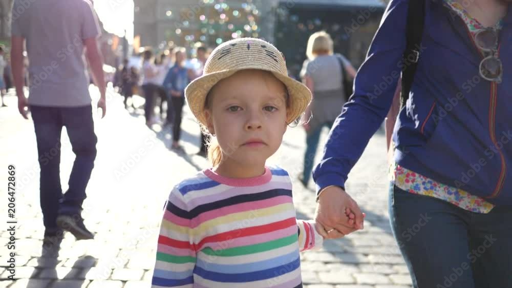 Little kid girl five years old slow motion walks in a city daytime holding mother hand in Wroclaw Poland Little kid girl five years old slow motion walks in a city daytime holding mother hand in Wroclaw Poland