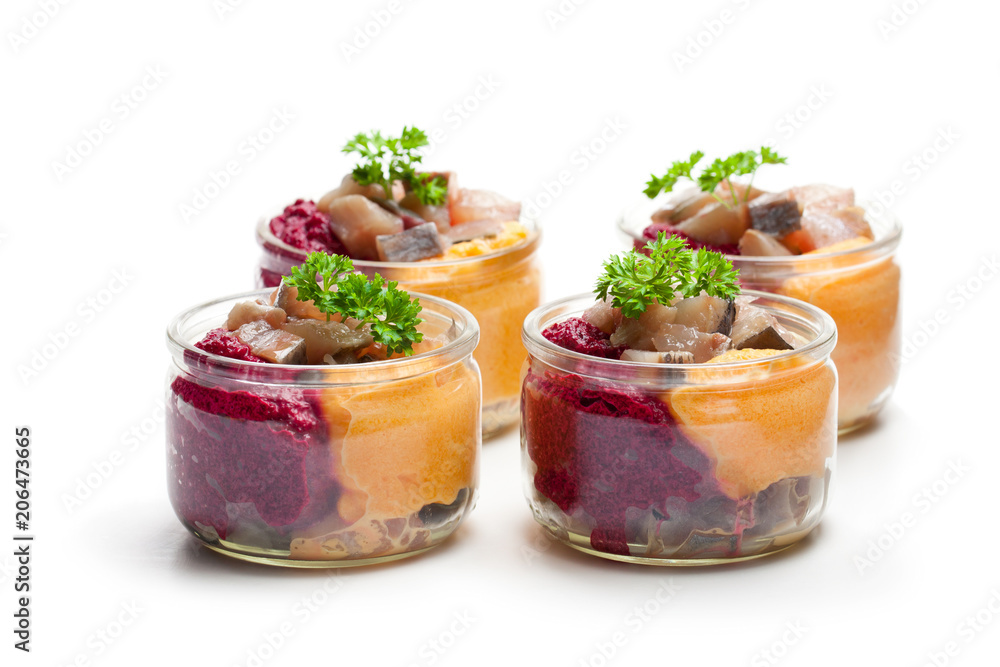 Herring salad with colorful vegetables in a small glass jars isolated on white Herring salad with colorful vegetables in a small glass jars isolated on white