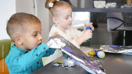 Cute kids in cafe, children sit at table and play the kinder surprise toys photo