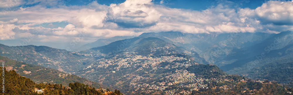 View from the observation deck of the Buddhist monastery Rumtek on the capital of Sikkim - the city of Gangtok and Himalayas under covering clouds.